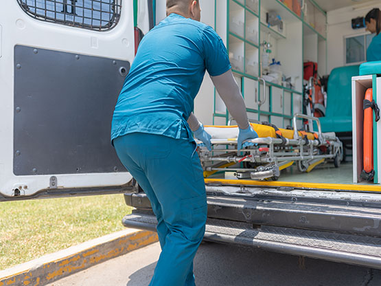 Rear view of an unrecognizable doctor pulling a stretcher out of an ambulance in the street